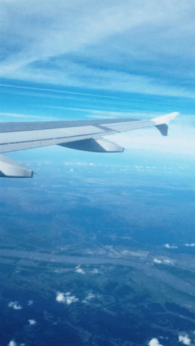the wing of an airplane is flying over some land