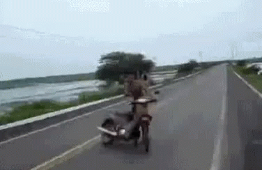 two motorcyclists riding on the road with a motor bike