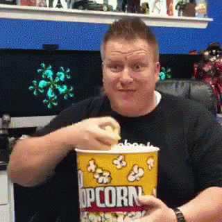 a man is holding a bucket with popcorn in it