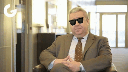 an elderly man wearing sunglasses and a suit