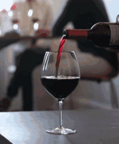 wine being poured into a glass in a dining room