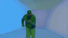 a man is standing in a green snowsuit