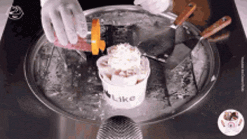 a person standing over a kitchen sink holding a cup of ice cream
