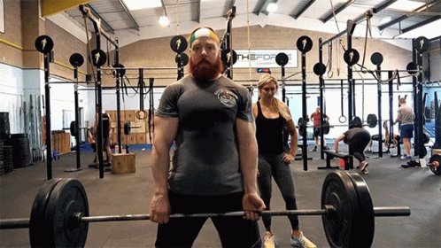 there are many people in a gym holding their arms on one end of a barbell