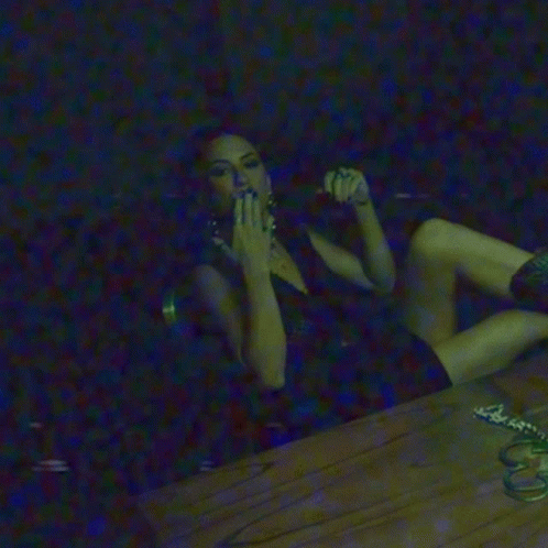 a girl sitting on the floor in the dark smoking a cigarette