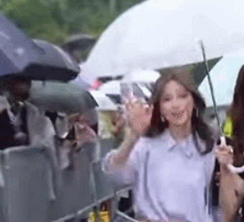 two women are holding umbrellas and waving at people