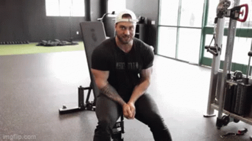 a guy is squatting on a stationary bench