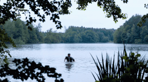 two people on horseback in a lake in the woods