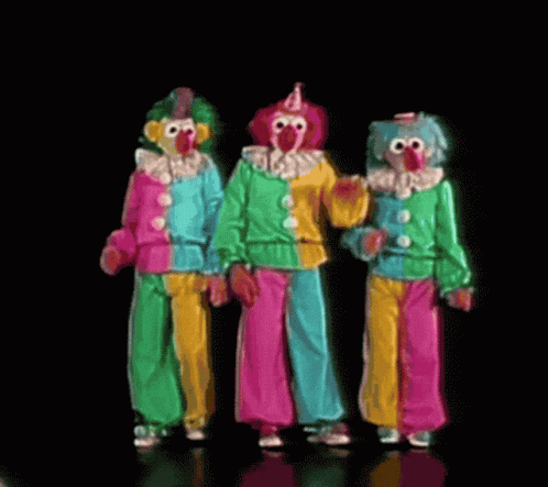 three clowns wearing colorful suits are standing side by side