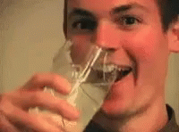 man drinking from a glass looking into the camera