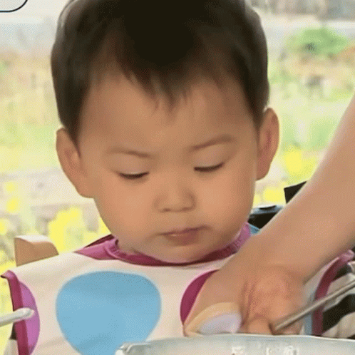 an infant baby sitting in a high chair and holding a spoon