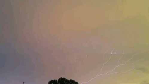 an image of lightning in the distance above trees