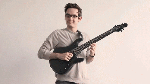 a man wearing glasses holding a guitar
