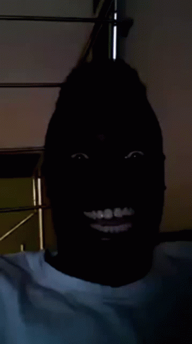 a black man wearing a black mask standing in a dark room