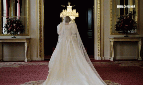 a bride in a wedding dress and white veil walking down the aisle