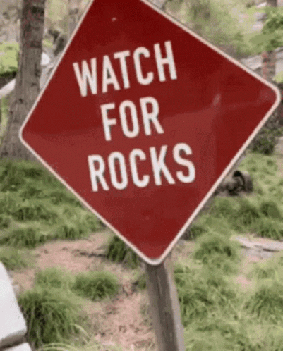 a watch for rocks sign is in a park