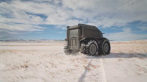a large truck driving through an open snowy field