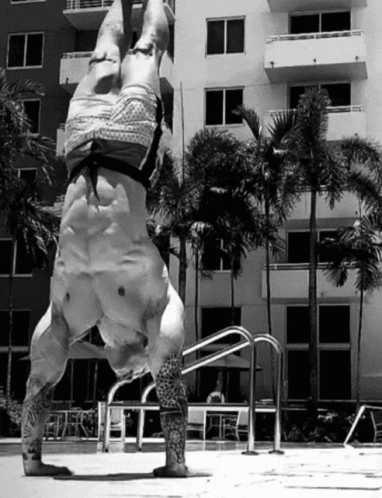 a statue of a man upside down near an apartment building