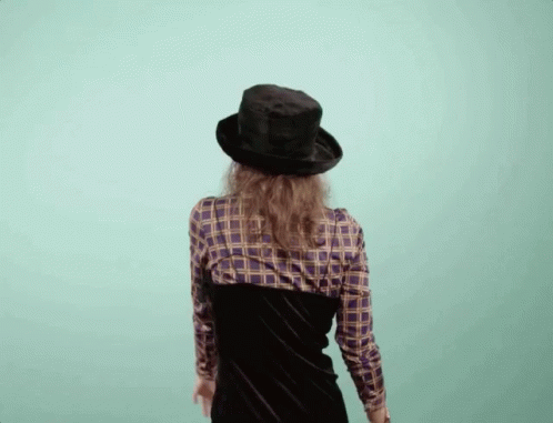 the woman in plaid shirt and hat walks