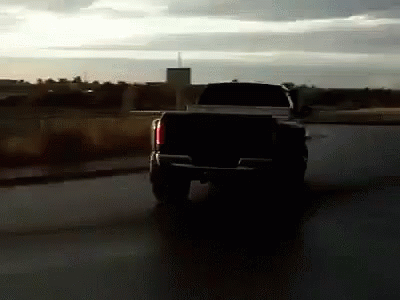 a black truck is driving down a road