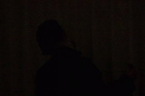 a person standing alone in the dark holding soing in their hands