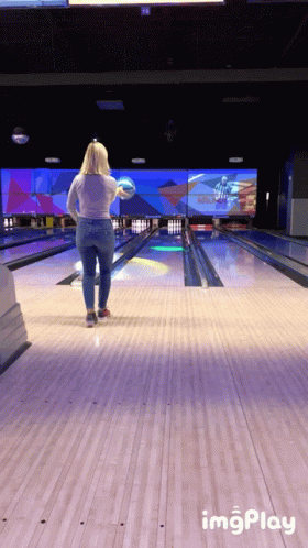 a bowling alley with a woman holding a bowling paddle