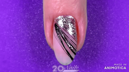 someones nail with white glitter and purple and silver stripes on it