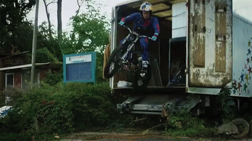 a man riding a bicycle off the back of a truck