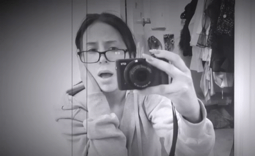 a woman in glasses taking a selfie with a camera