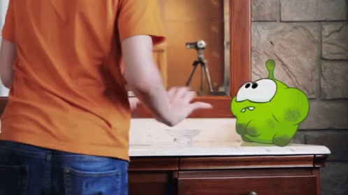 a person looks into a bathroom mirror at a green stuffed animal