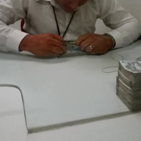 a man is sitting at a desk counting coins