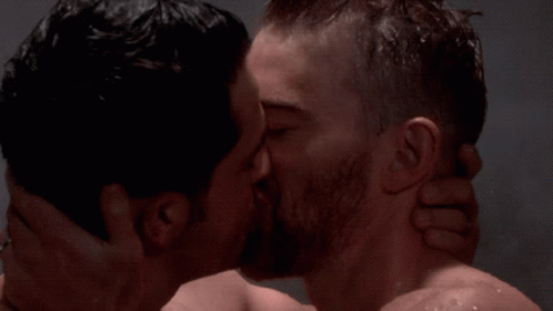 two men who are kissing each other while one gets wet