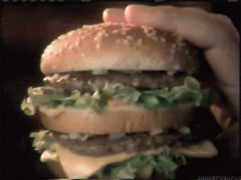 a hand holding a hamburger that is topped with lettuce