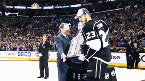 two people in black and white outfits with a trophy on ice