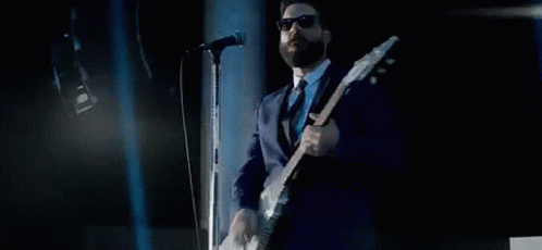 a man in suit and tie with an electric guitar