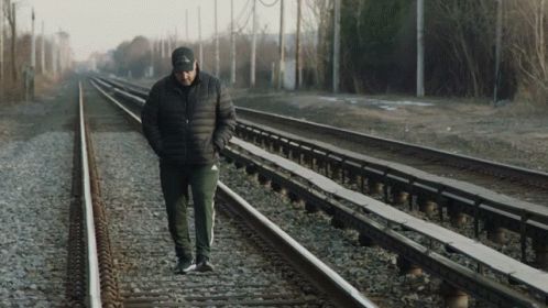 the man is walking on the railway tracks