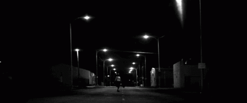 a lone person walks down an empty street at night
