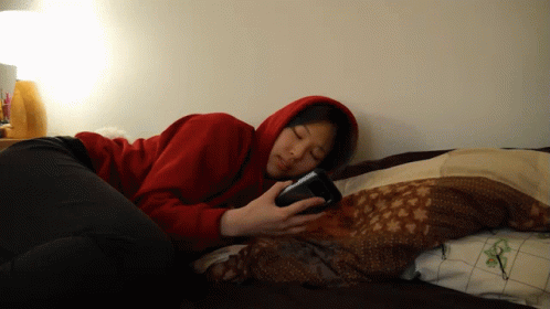 a woman in a blue sweatshirt laying on top of a bed