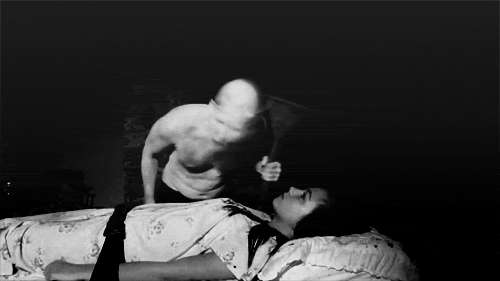 black and white po of man on a bed with the woman facing him