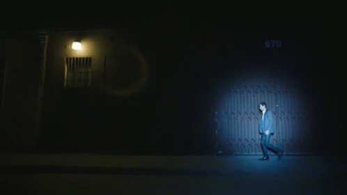 a man in the dark walking towards an open door