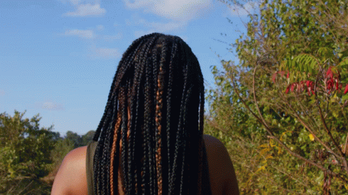 a woman with long dreadlocks looking at the sky