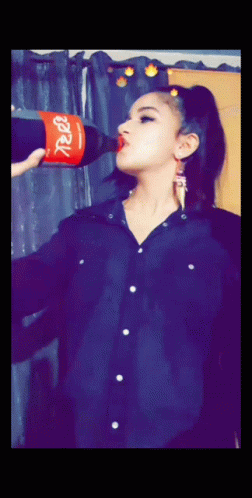 a woman holding up a soda bottle to the air