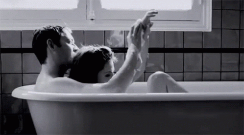 a man and woman in a bathtub with their feet up