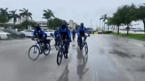 three men riding bikes down a wet street