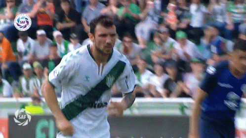 a soccer player wearing white and green runs
