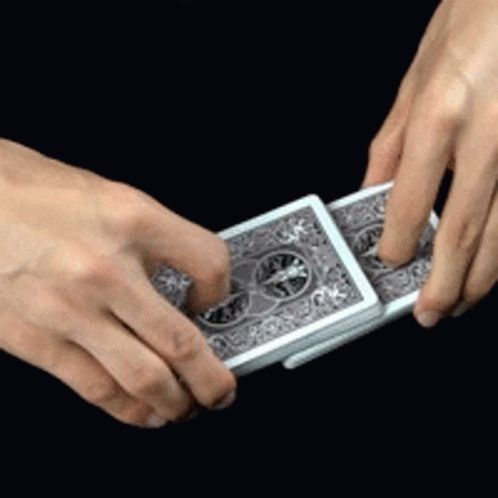 two hands holding a set of cards in one hand and the other is pointing on it