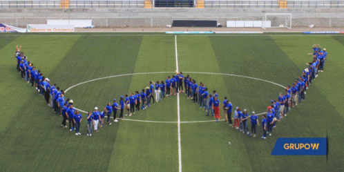a large group of people standing around in the shape of an arrow on a soccer field