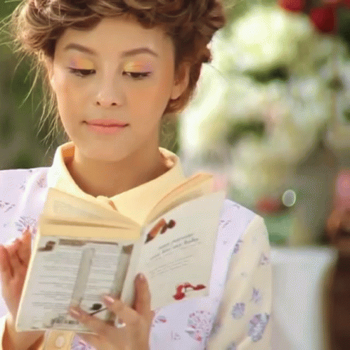 a woman is dressed in an elaborate kimono and is reading the book