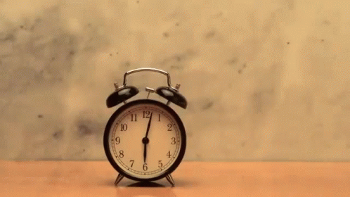 an alarm clock in front of a grey wall