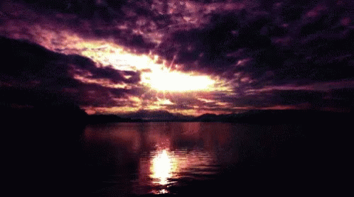 there is purple clouds in the sky above water